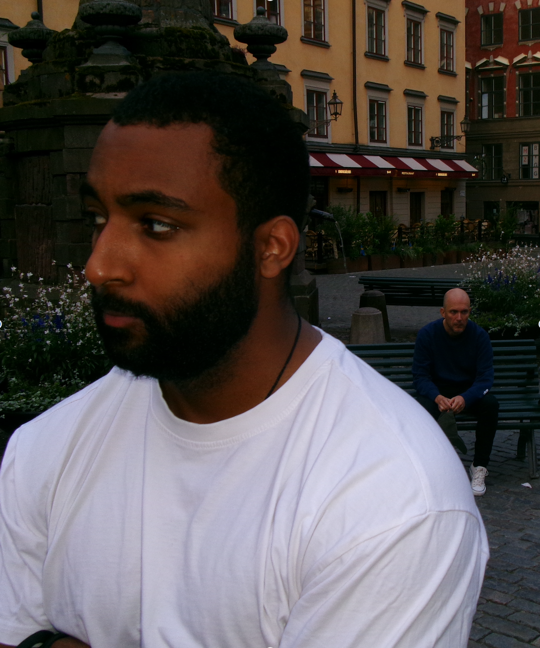A man in a white t-shirt standing in a Stockholm square
